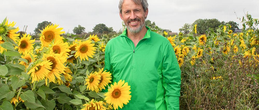 Stolz zeigt Dirk von der Ehe seine bestellten Beete mit langen Reihen Ruccolapflanzen, Kohl, Porree und Blühstreifen mit Sonnenblumen