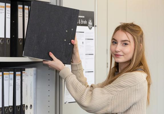 Die Auszubildende Nina Evers sortiert Akten in den Schrank