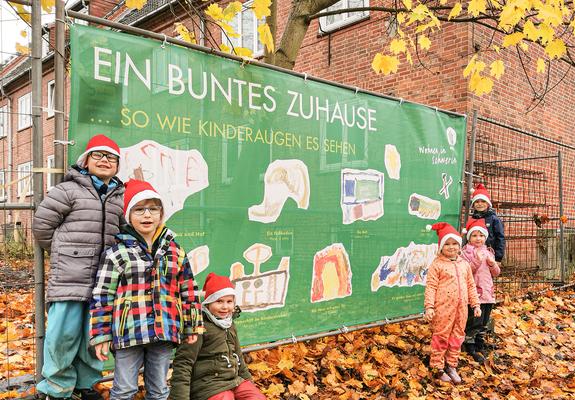 Die Kinder Andrijus, Caspar und Evelyn sowie Emily-Sophie, Linea und Oskar aus der Handwerks-Kita „Alles im Lot“ präsentieren stolz ihre Bauzaunplane