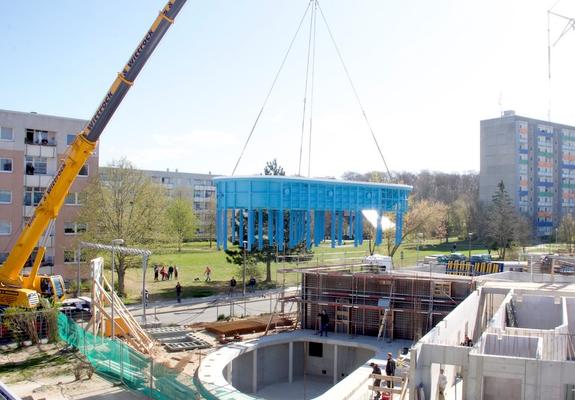 Technische Maßarbeit. Mit einem Spezialkran wird das nierenförmige Schwimmbecken vom Schwerlasttransporter in den vorgefertigten Betonausschnitt gehoben