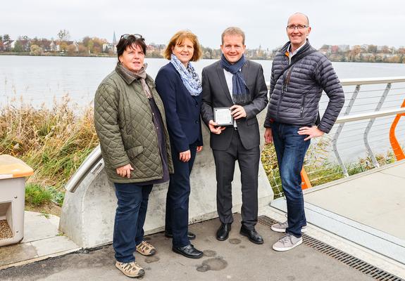 Besonders schön strahlt die Brücke in der Dunkelheit und erschafft ein wunderbares Panorama vomSeeufer. Gleichzeitig setzt das Bauwerk die Silhouette der Landeshauptstadt von der Wasserseite gekonnt in Szene.