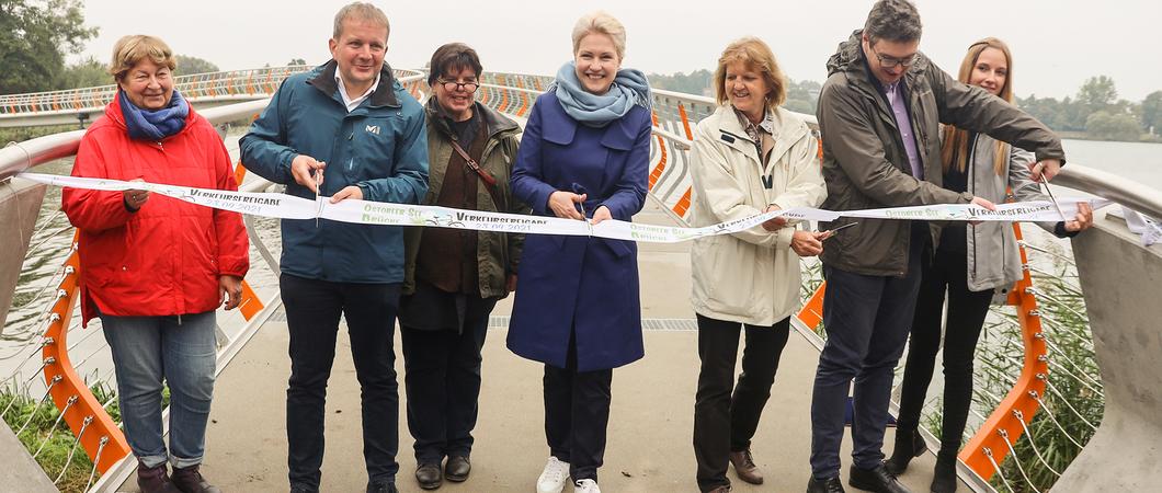 Besonders in den Abendstunden, wenn es dämmert und die  insektenfreundliche Beleuchtung in den Handläufen der Brücke zu strahlen beginnt, zeigt sich die neue Querung über den Ostorfer See in ihrer ganzen Schönheit.