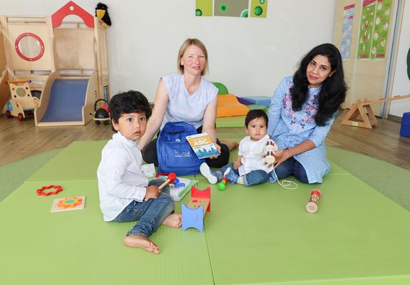 AWO-Mitarbeiterin Katharina Koslow (Mitte) zeigt Mahbuba Afroja (r.) den Willkommensrucksack der Stadt mit dem Familien ABC und vielen nützlichen Dingen, Foto: maxpress