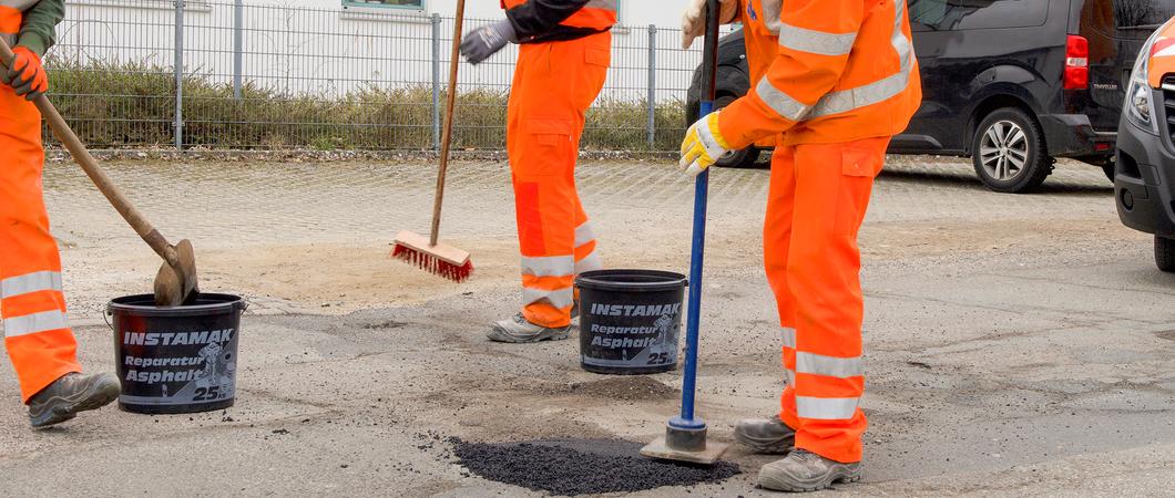 Ein Schlagloch im Ziegeleiweg wird mit Kaltasphalt gefüllt