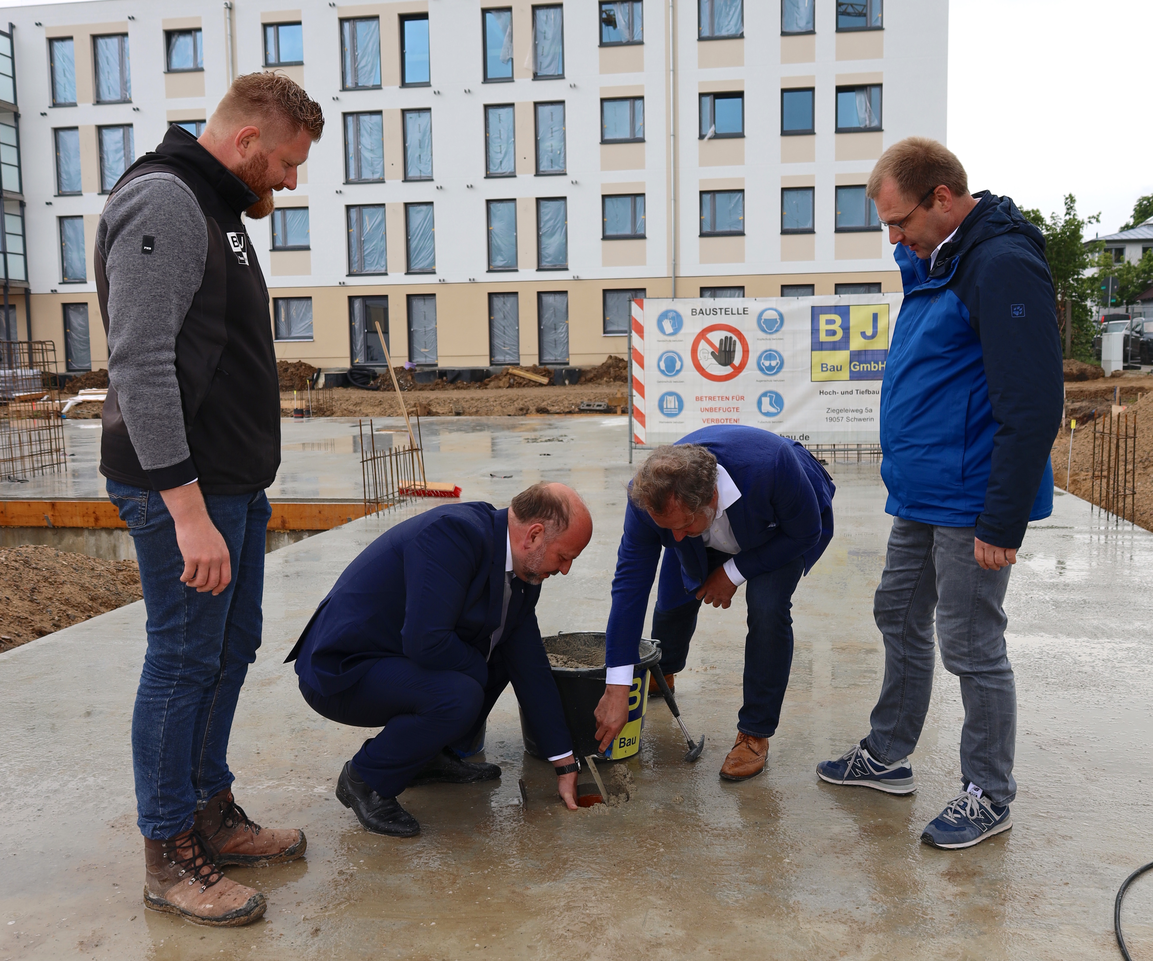 Bauleiter Florian Ribbeck (l.) beobachtet gemeinsam mit Jens Leupold, DRK Kreisgeschäftsführer SN (r.), wie Tom Neugebauer, Präsident DRK-Schwerin (2.v.l.) und Architekt Jens-Peter Kasbohm den Grundstein legen